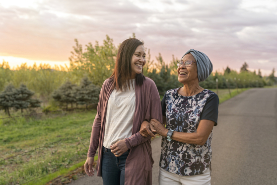 Woman walking arm in arm with older woman outdoors